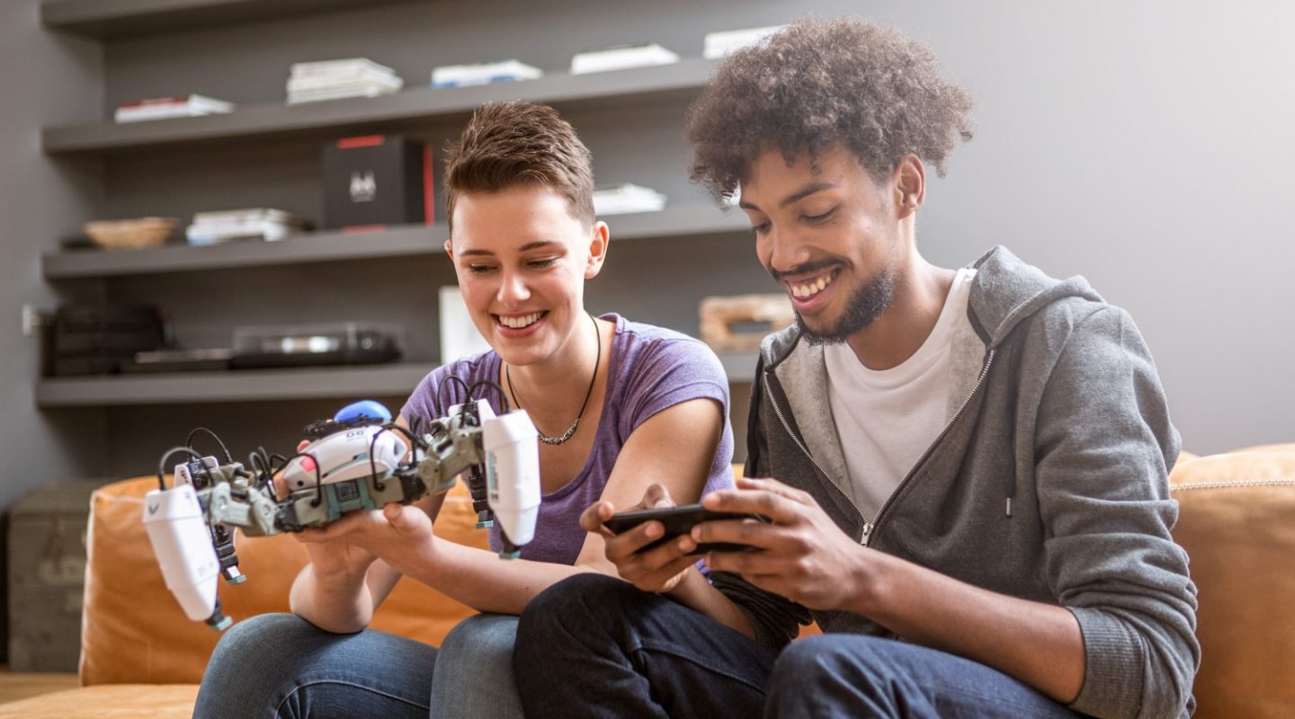 Couple on sofa playing with Mekamon gaming robot for campiagn photography